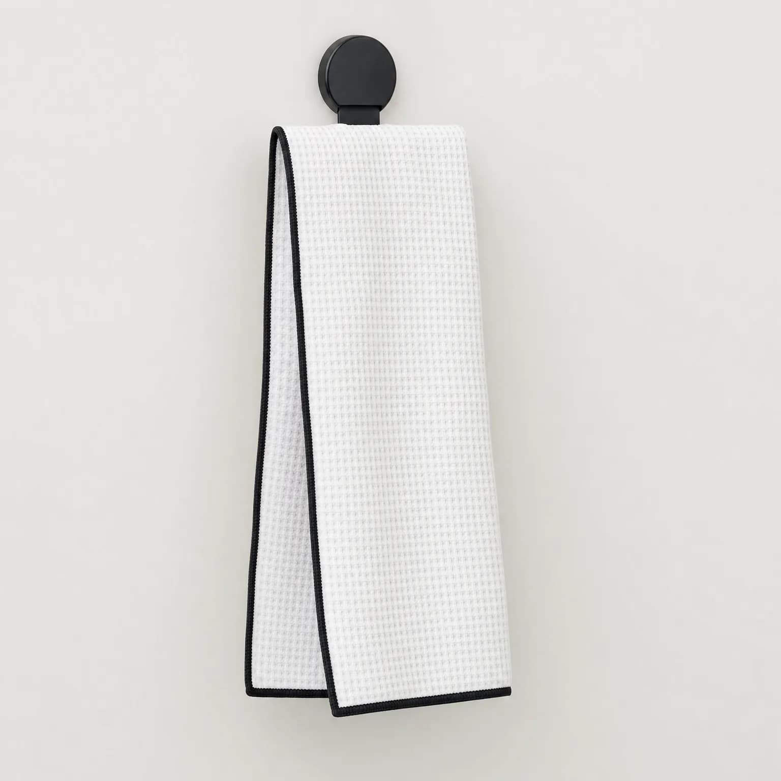 White waffle-weave golf towel with black contrast piping and magnetic clip
